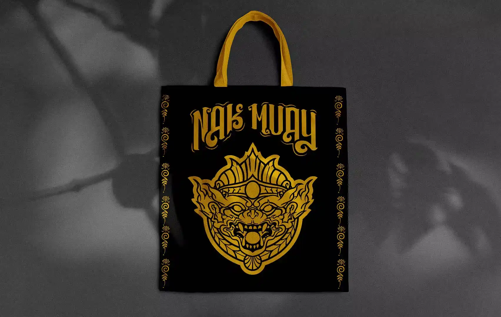 Totebag negra, con asa amarilla y el imagotipo de Nak Muay en amarillo